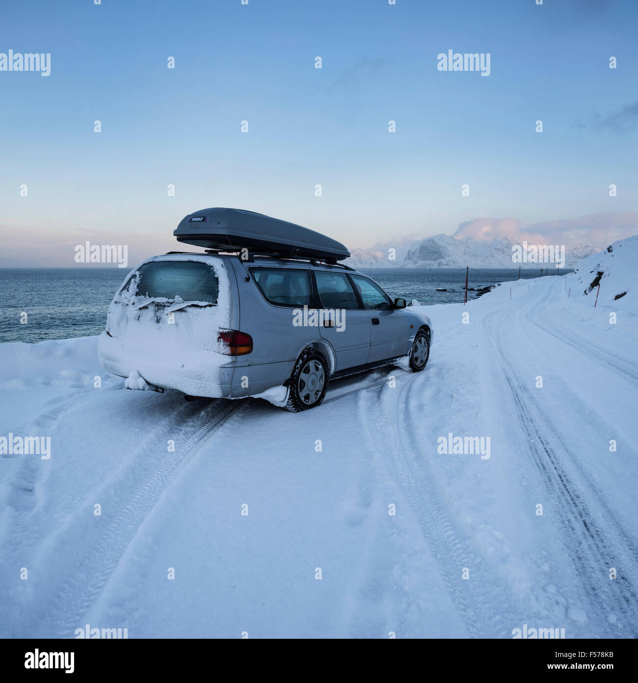 Car with ski rack parked on snowy road near ocean, Lofoten Islands, Norway Stock Photo