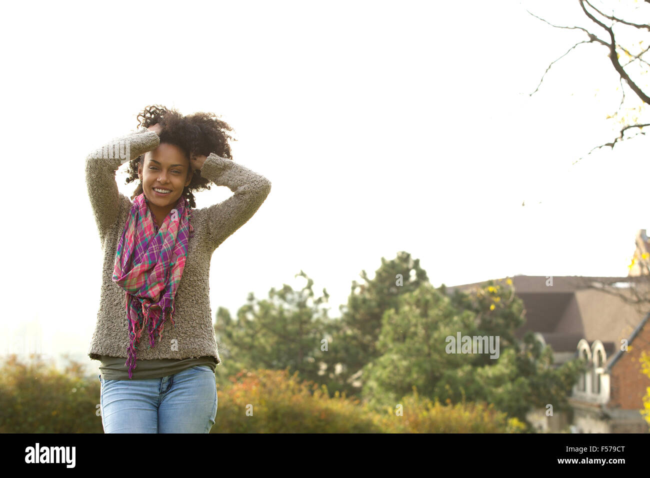 Portrait of a smiling young african american woman with hands in hair ...