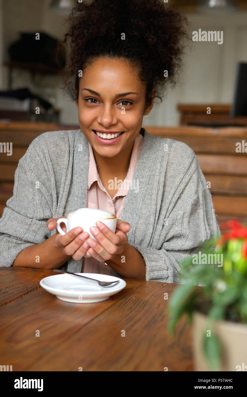 Portrait of a smiling young woman holding cup of coffee Stock Photo - Alamy