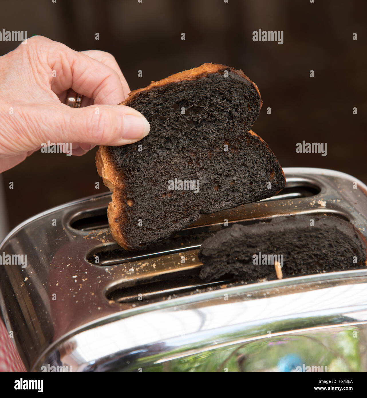 Slice of burnt toaster being removed from a toaster Stock Photo