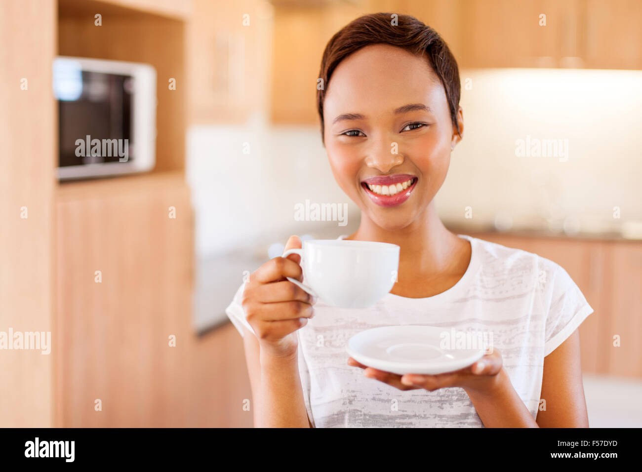 pretty young African woman drinking coffee in kitchen Stock Photo Alamy