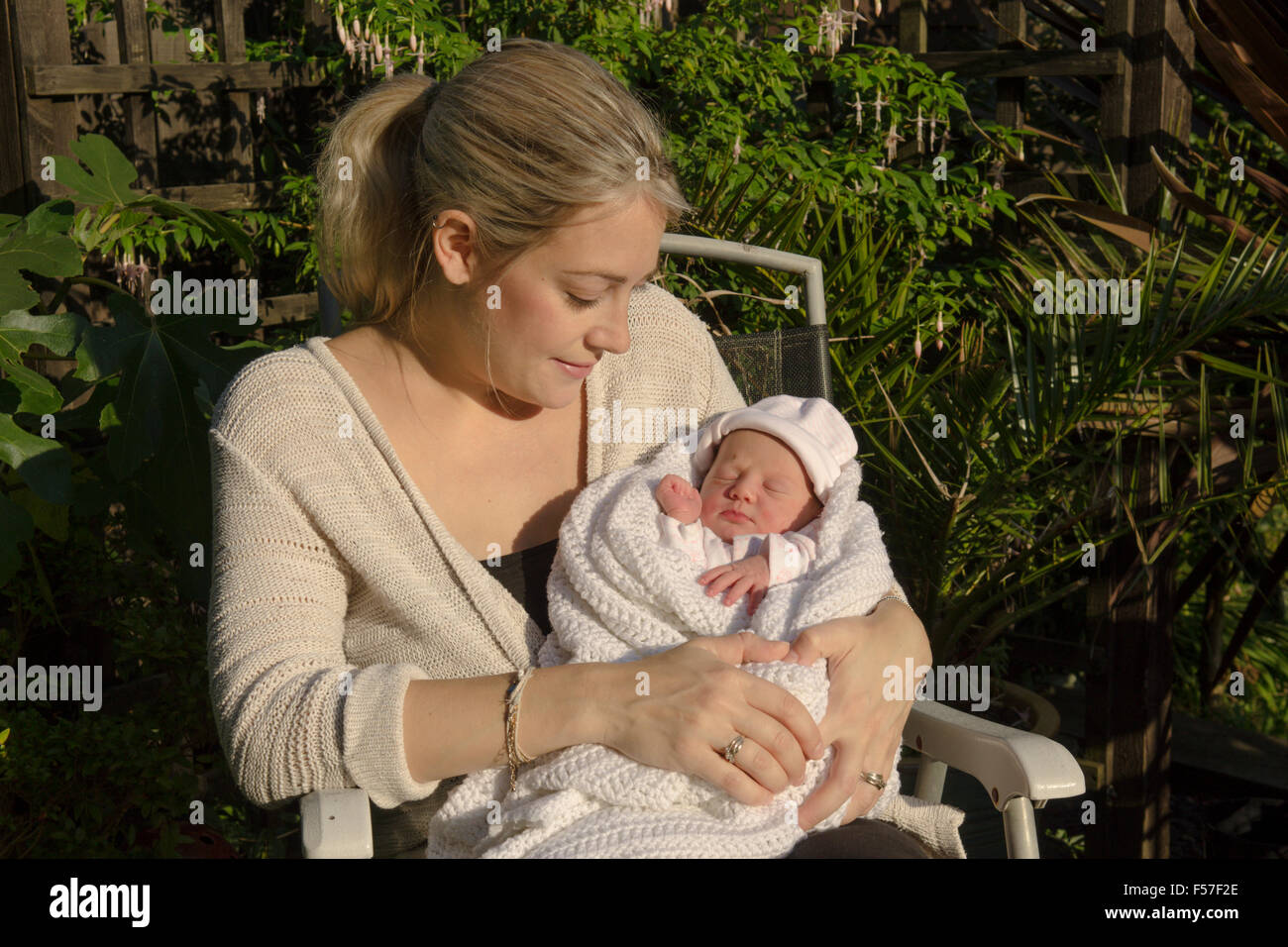 Mother with one day old baby girl sitting in sunshine. Baby slightly jaundiced. UK. Stock Photo