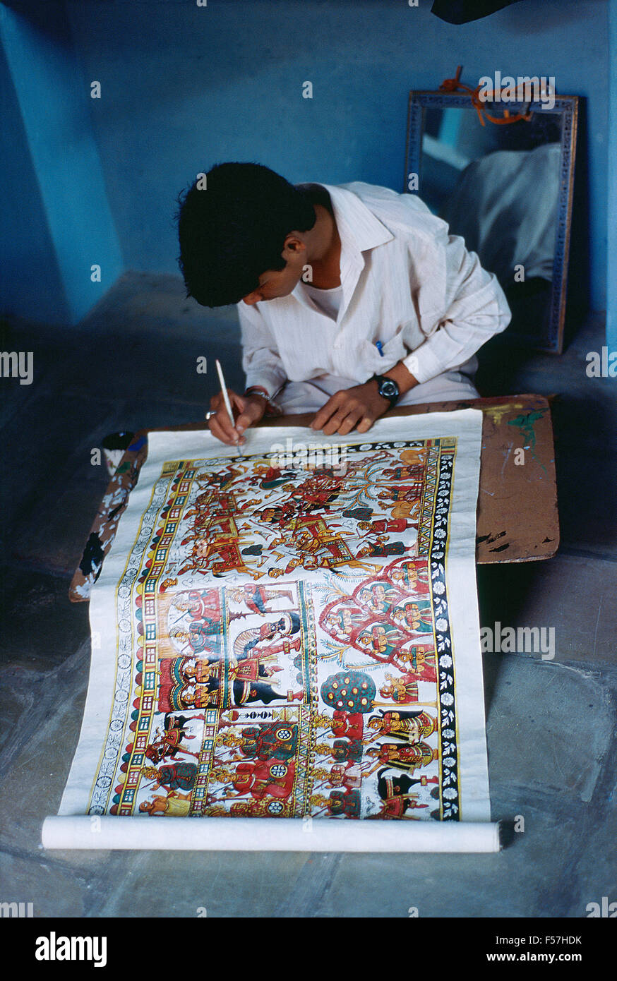 Young man painting a 'Pabuji ki phad' ( i.e. a traditional scroll painting representing the life of the hindu hero-god Pabuji). Stock Photo