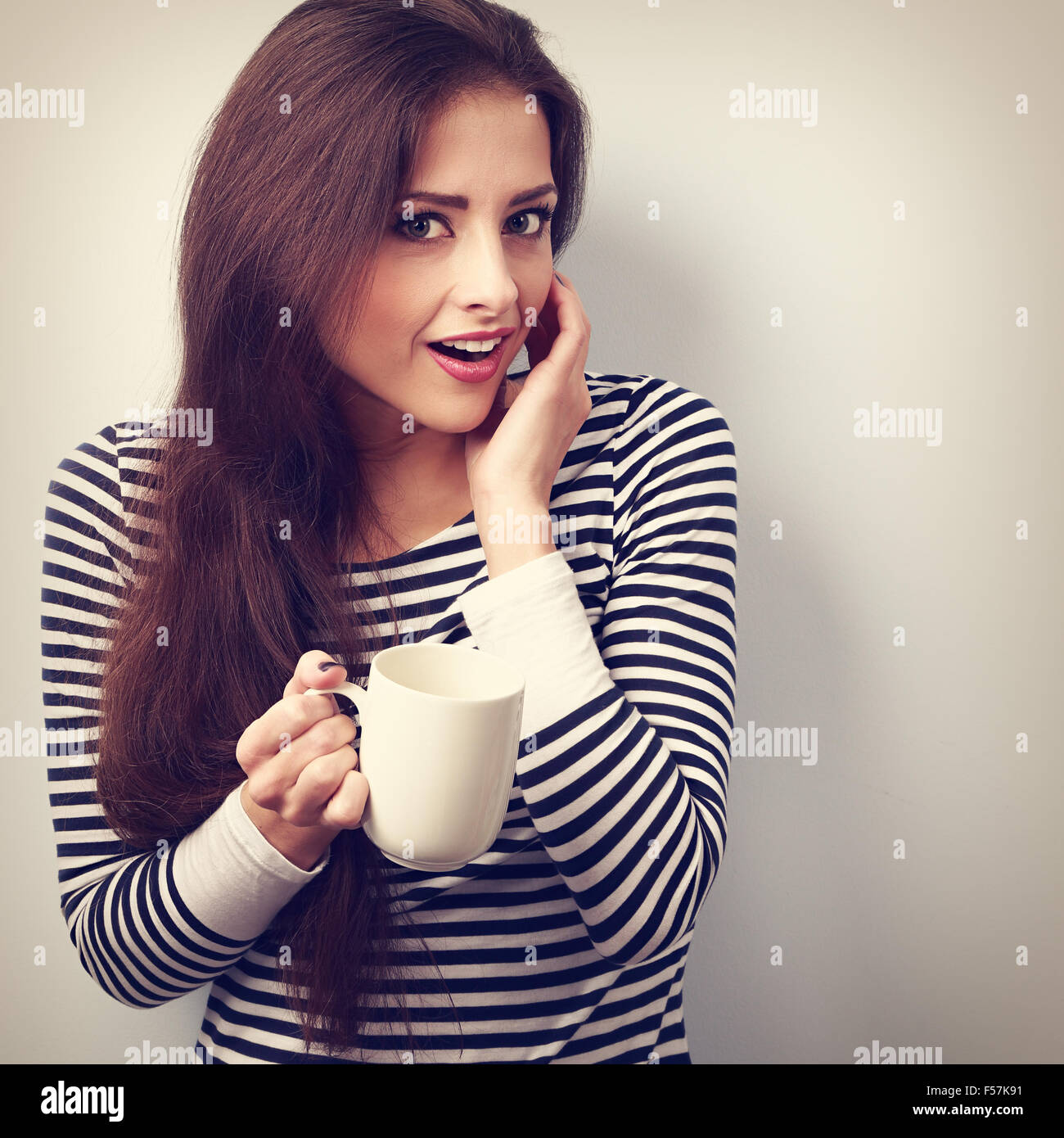 Fun surprising young woman with opened mouth holding cup of tea. VIntage closeup portrait Stock Photo