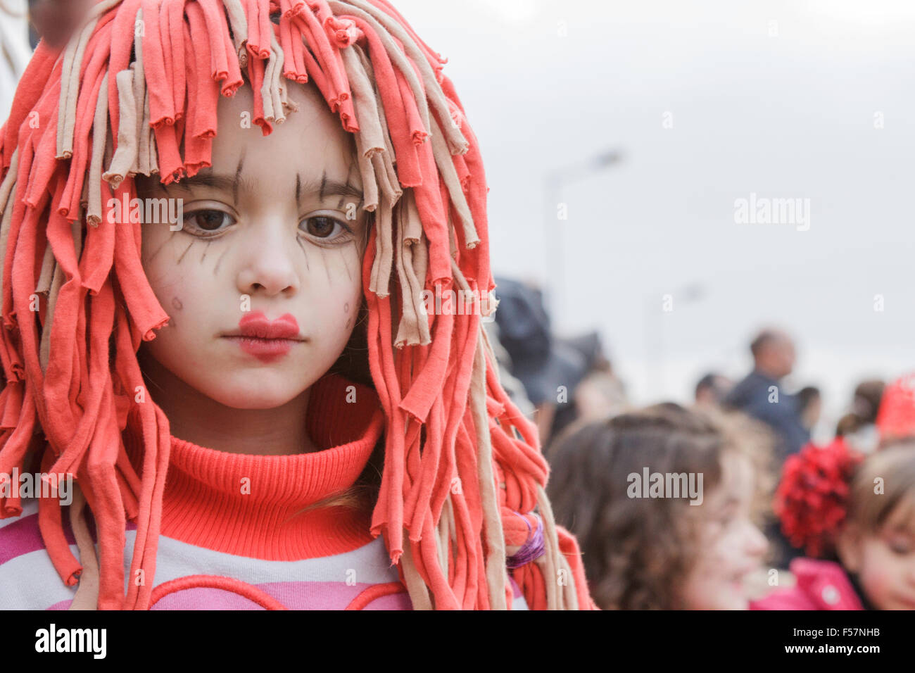 Portrait of the beautiful face of a young girl in a red and beige, fabric, tassled wig with make-up - Mealhada Carnaval/ Carnival street parade Stock Photo