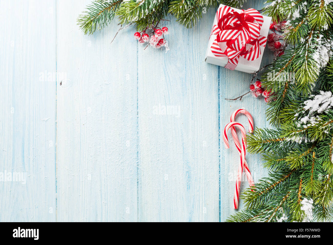 Christmas gift box, candy cane and fir tree branch on wooden table. Top ...