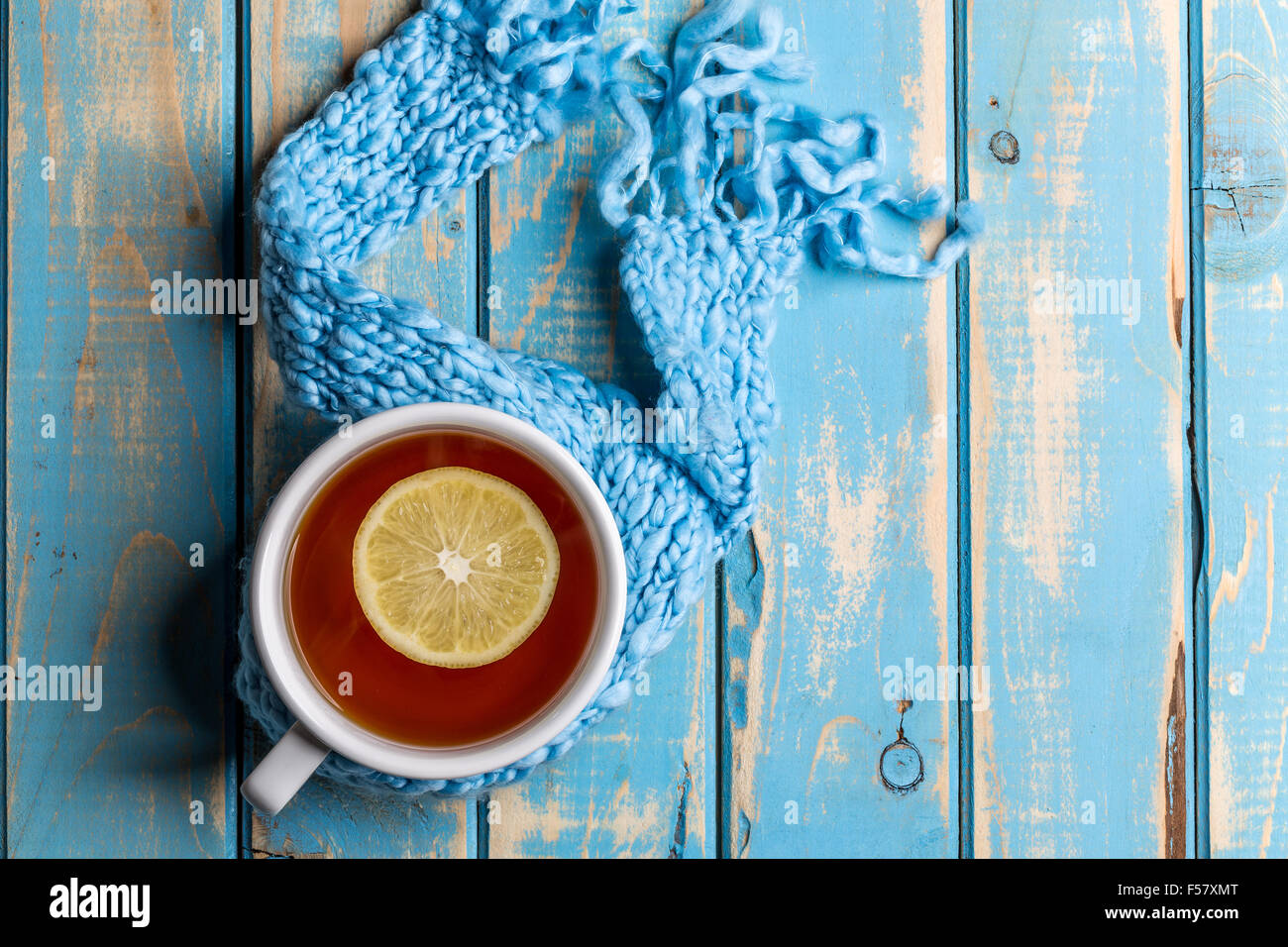 Cup of hot tea with lemon dressed in winter scarf Stock Photo