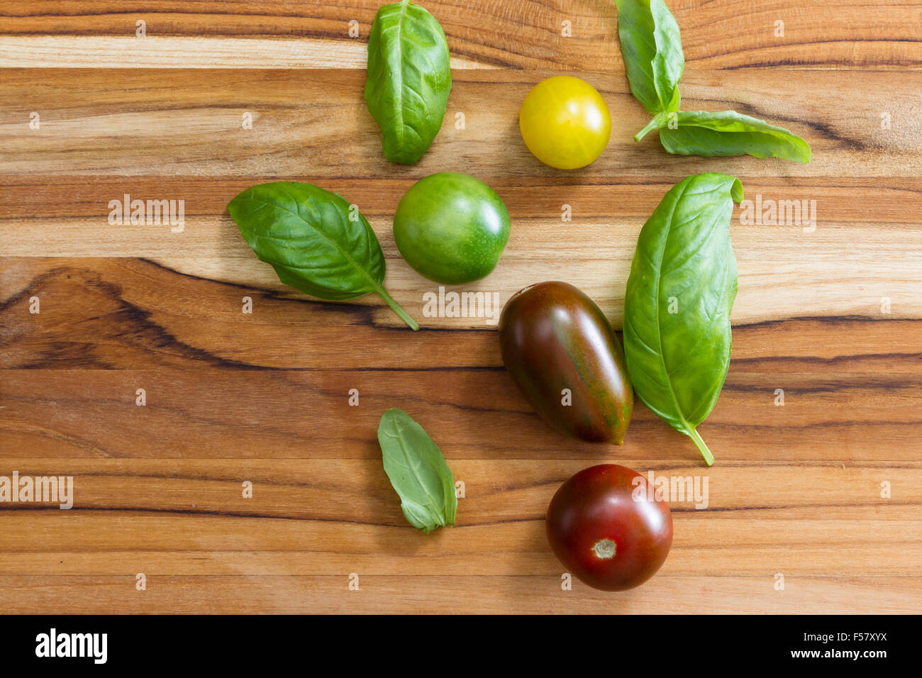 fresh basil leaves and cherry tomatoes on a wooden table Stock Photo ...