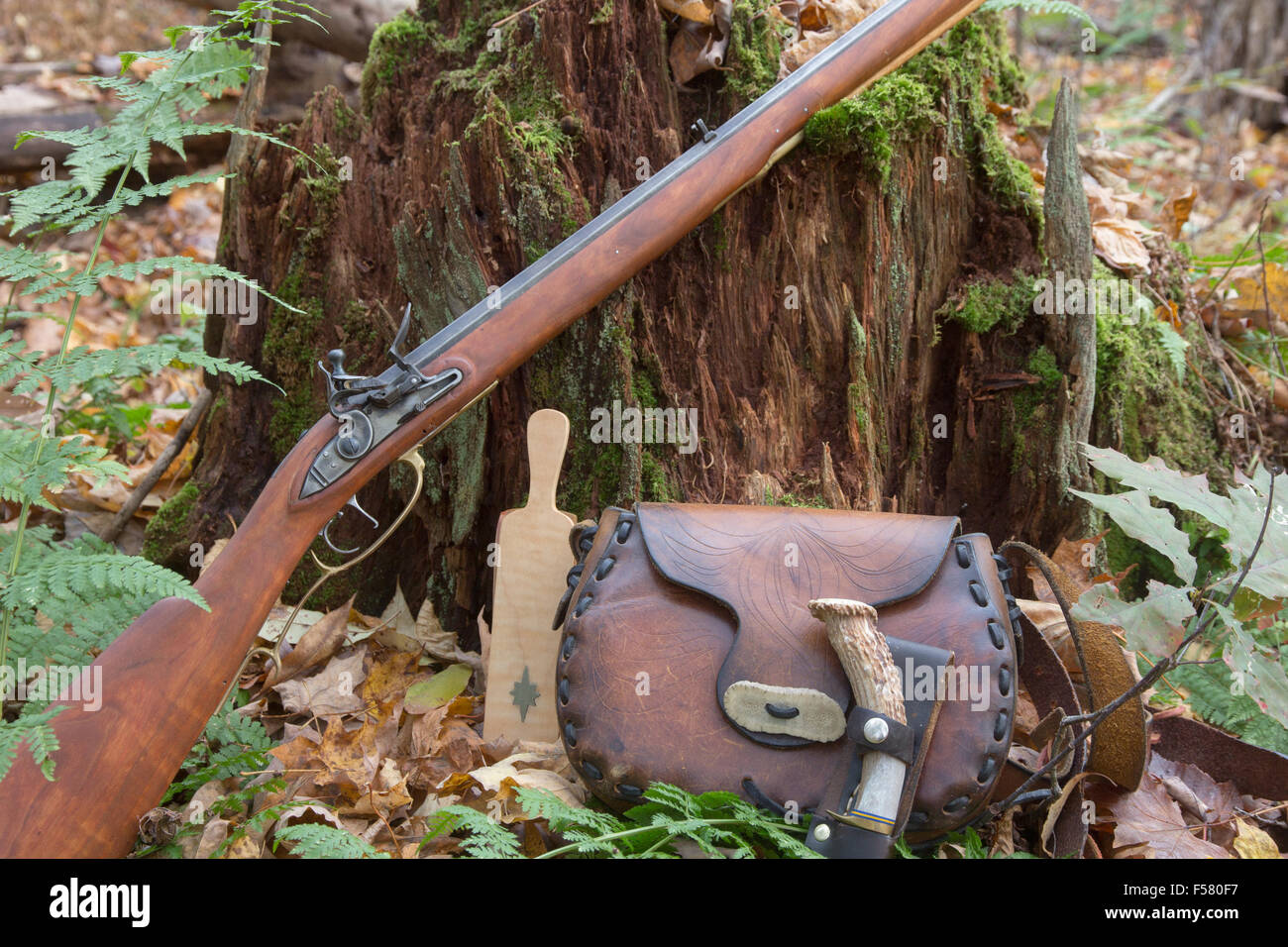 A hand-made flintlock rifle and accessories adorn a rotting stump