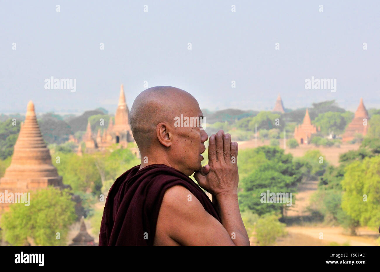 Buddhist Monk with hands together praying on top of the Shwesandaw Pagoda in Bagan, Myanmar, formerly Burma,  Southeast Asia Stock Photo