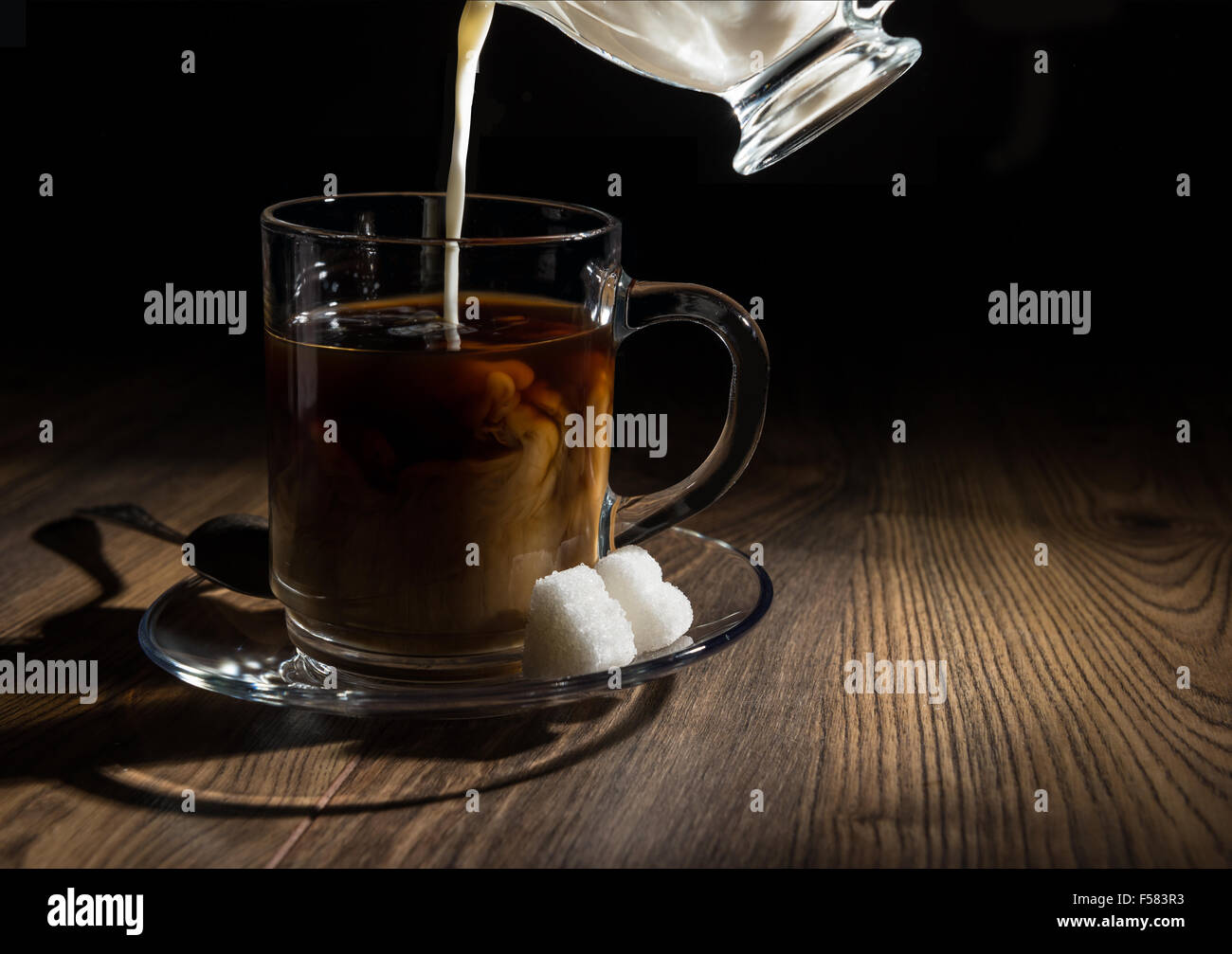 Ice coffee in glass mug with milk and cinnamon on wooden table in the  garden Stock Photo - Alamy