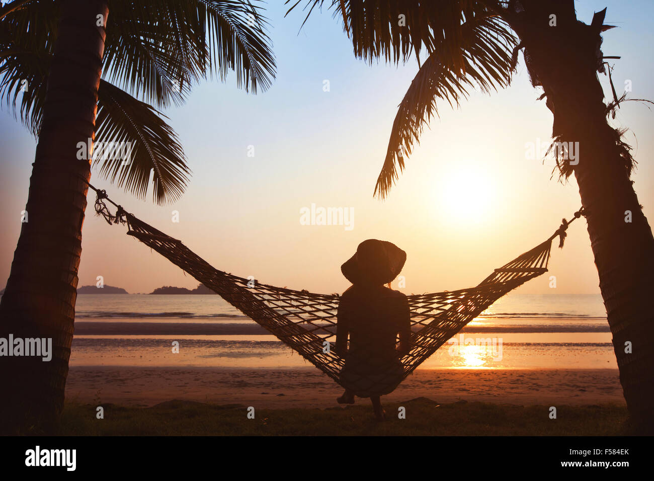 woman relaxing in hammock at sunset on the beach Stock Photo