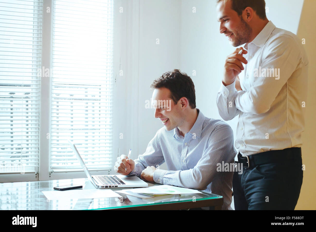 two young business men laughing in front of computer Stock Photo