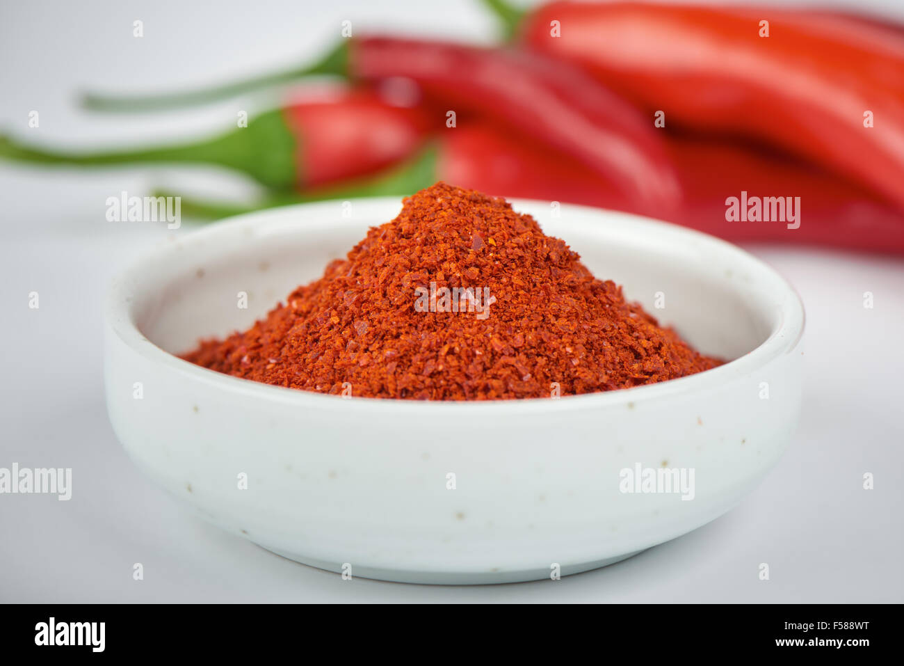 closeup of Korean chili pepper powder with chili peppers, on a white