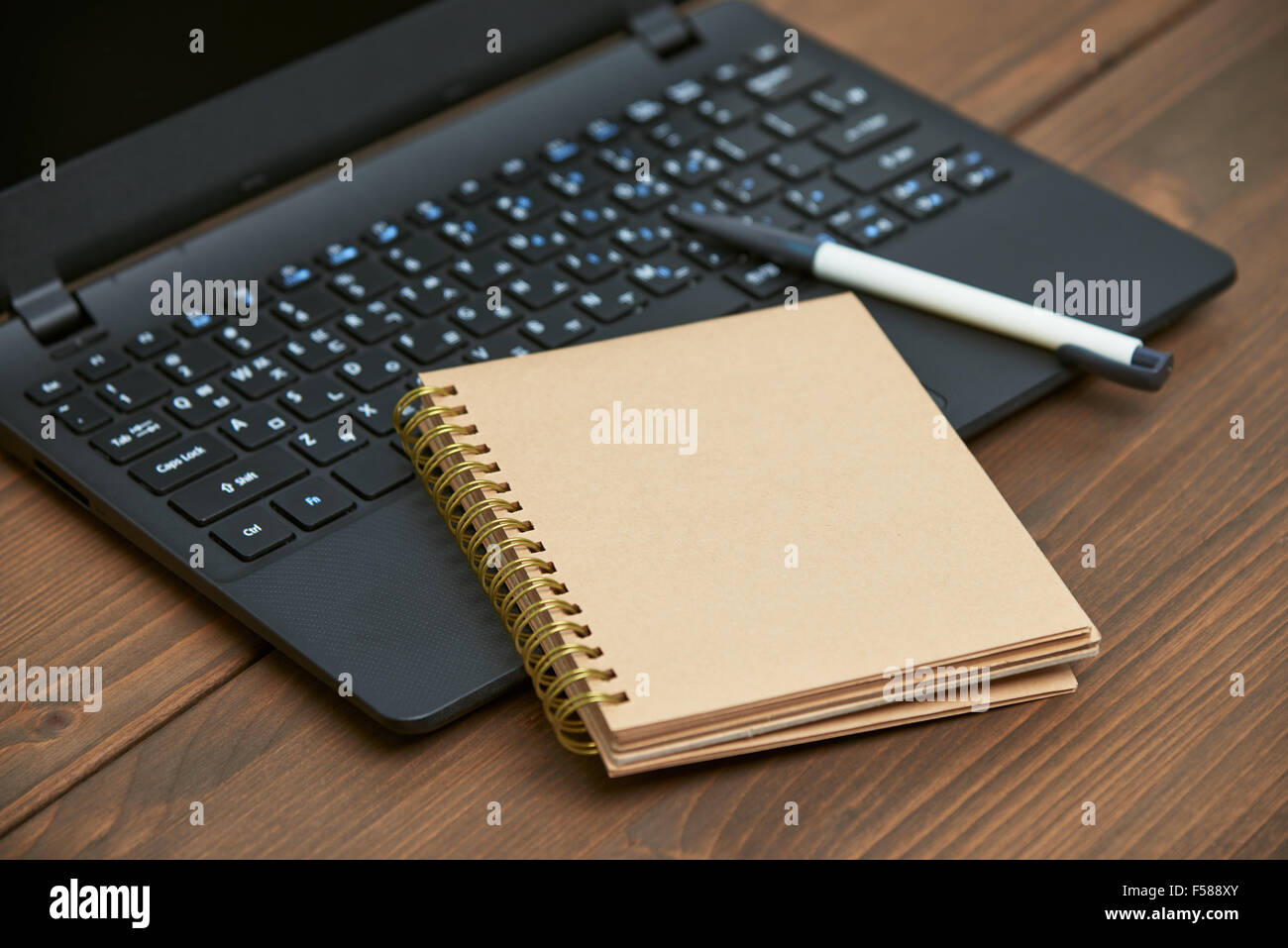 laptop computer and memo note with ballpoint pen on a wooden desk Stock Photo
