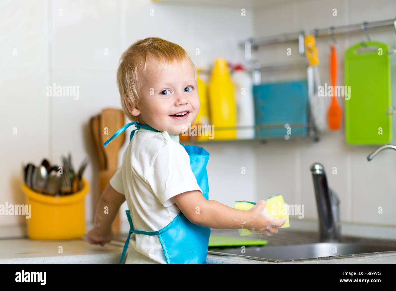 Little boy helping mother washing dishes in the kitchen Stock Photo