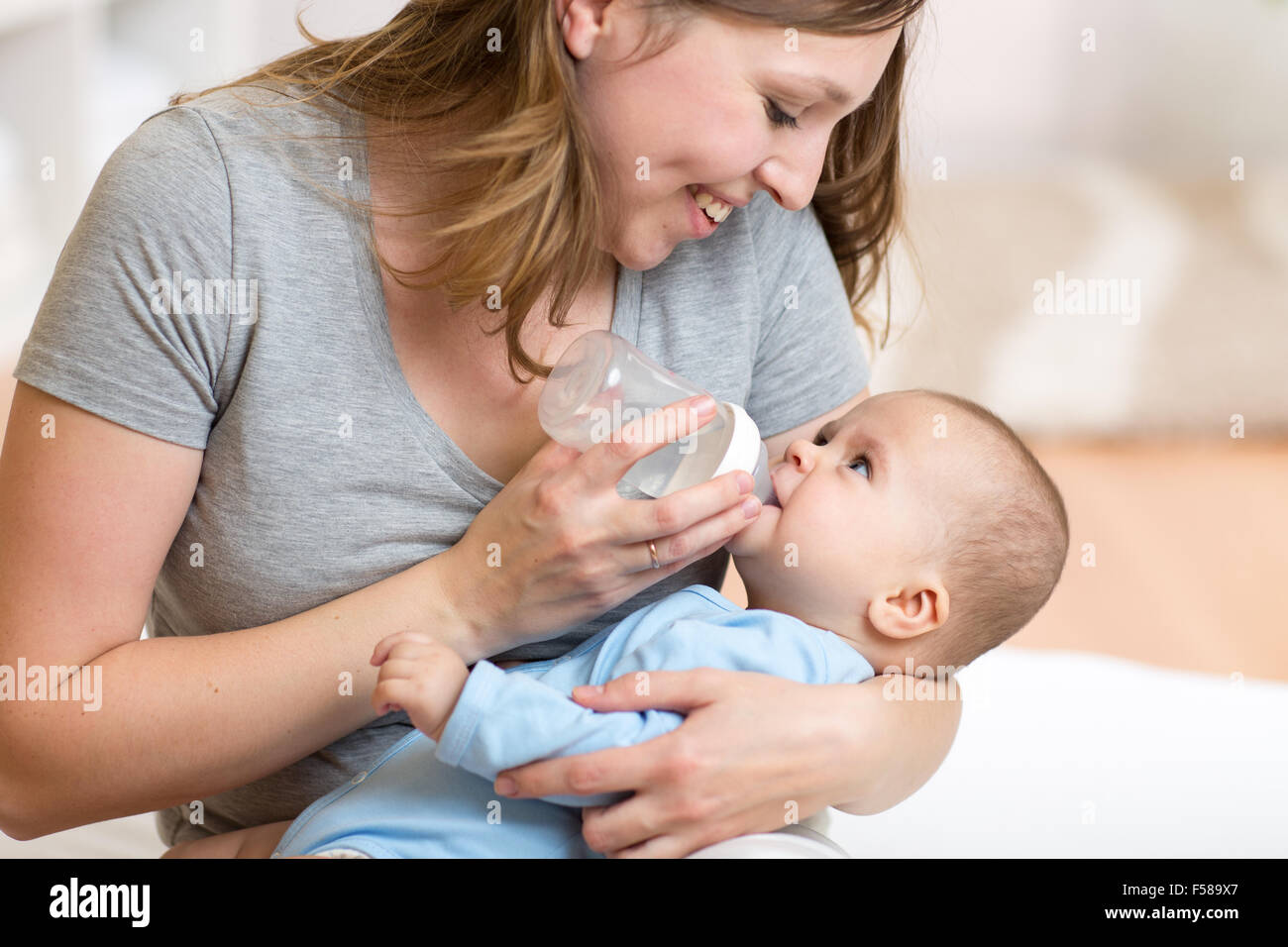 cute mother at home feeding baby with a milk bottle Stock Photo