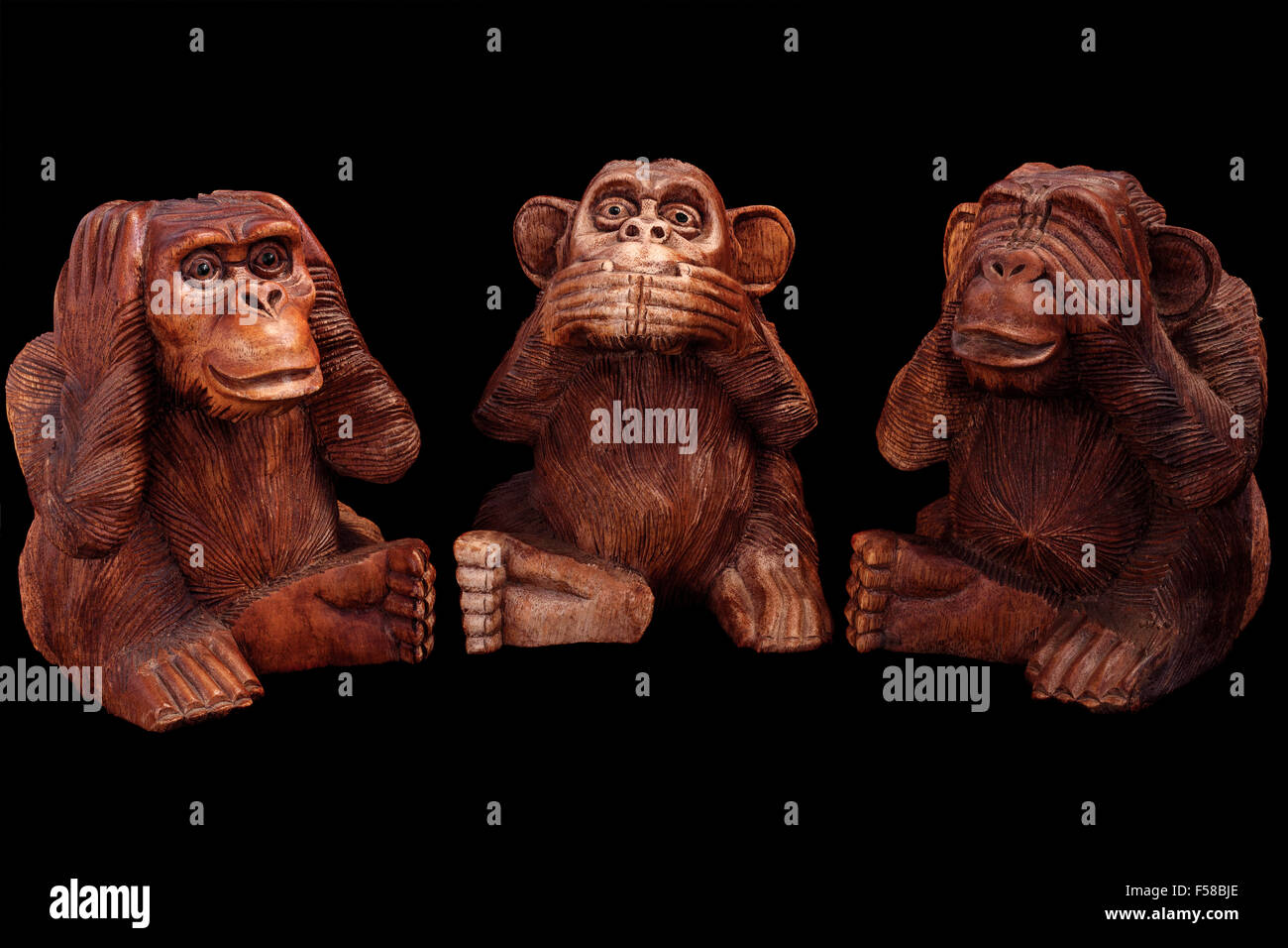 Three wise monkeys. Figurines of wood on a black background. Stock Photo