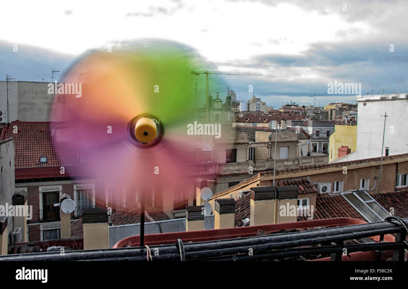 Rainbow color pinwheel spinning over the roof of the city rainy windy ...