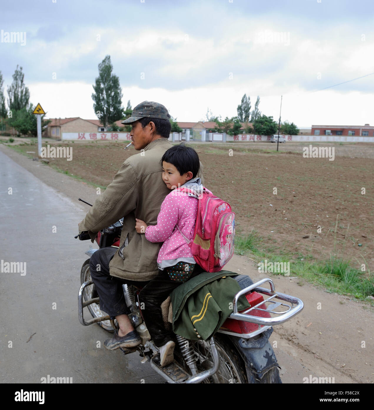 A Chinese father rides his daughter with a motorcycle in Haiyuan, Ningxia, China. Stock Photo