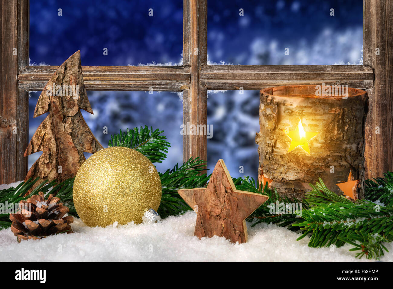 Christmas, Advent or winter seasonal arrangement on a window sill, decorated with snow, with cozy candle light, ornaments and fi Stock Photo