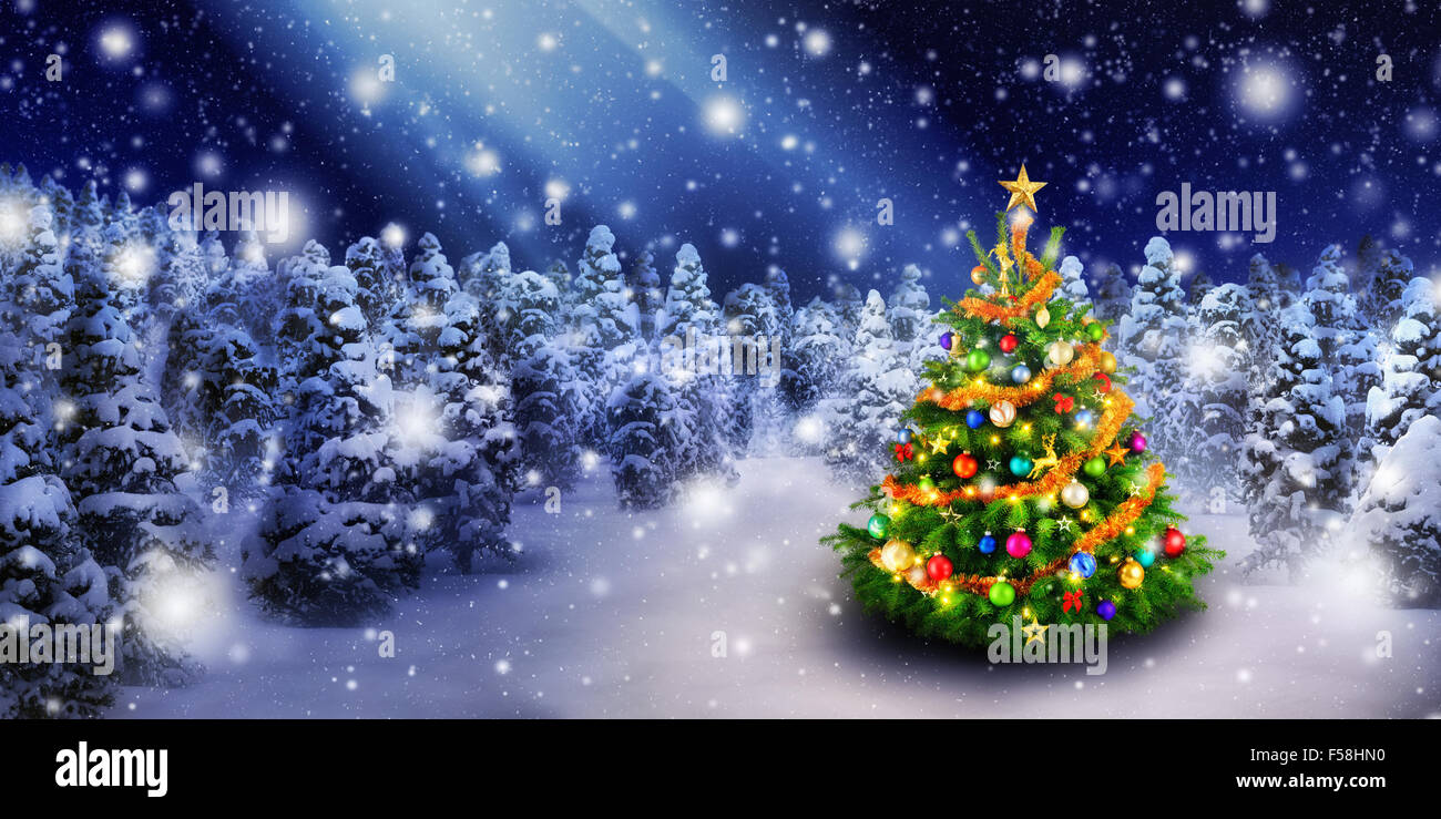 Magnificent colorful Christmas tree outdoor in a snowy night with a beam of magical light in the sky, for the perfect Christmas Stock Photo