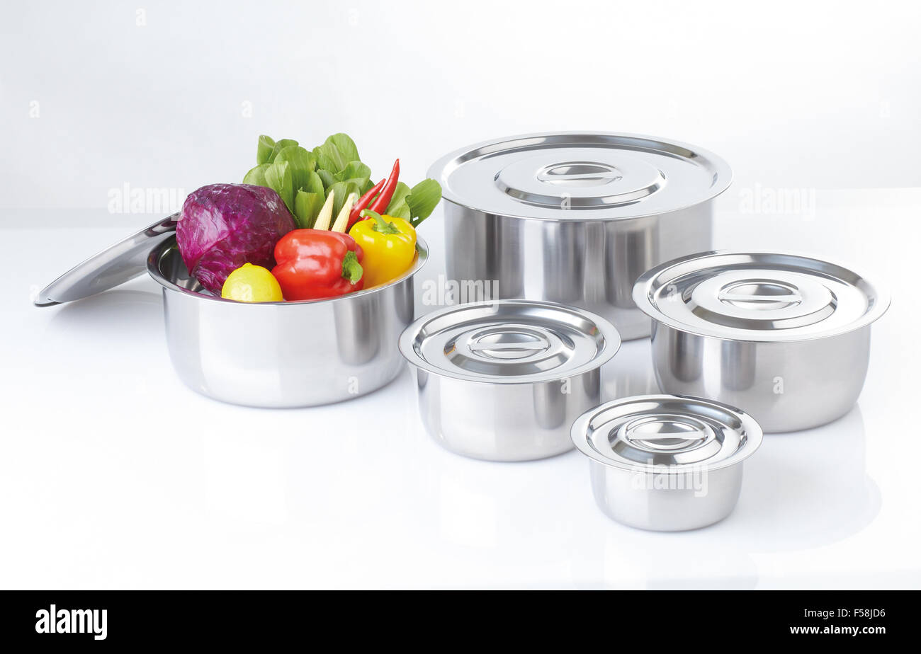 Set of stainless pots with lids and vegetable Stock Photo
