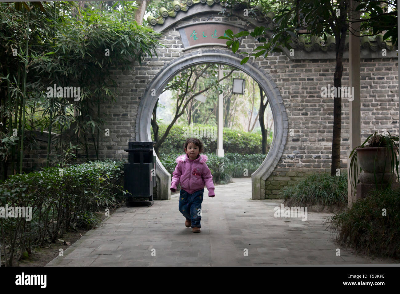 A little girl runs at an old garden at an old town called Gucheng in Pixian at the outskirts of Chengdu in China. Stock Photo