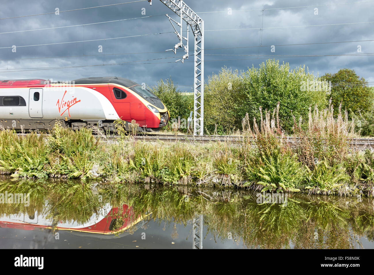 Virgin train and overhead wires with canal in foreground Stock Photo