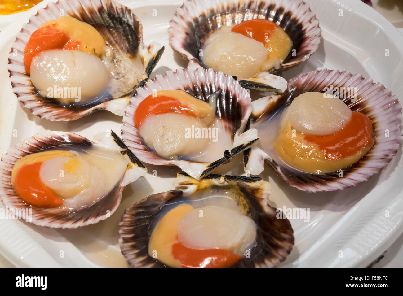 Scallops in shells on plate of hors-d'oeuvres or entradas in food counter in Spanish market in Madrid Stock Photo