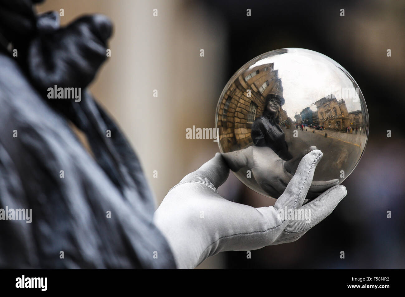 A street artist holds a metallic sphere that reflects an old city street Stock Photo