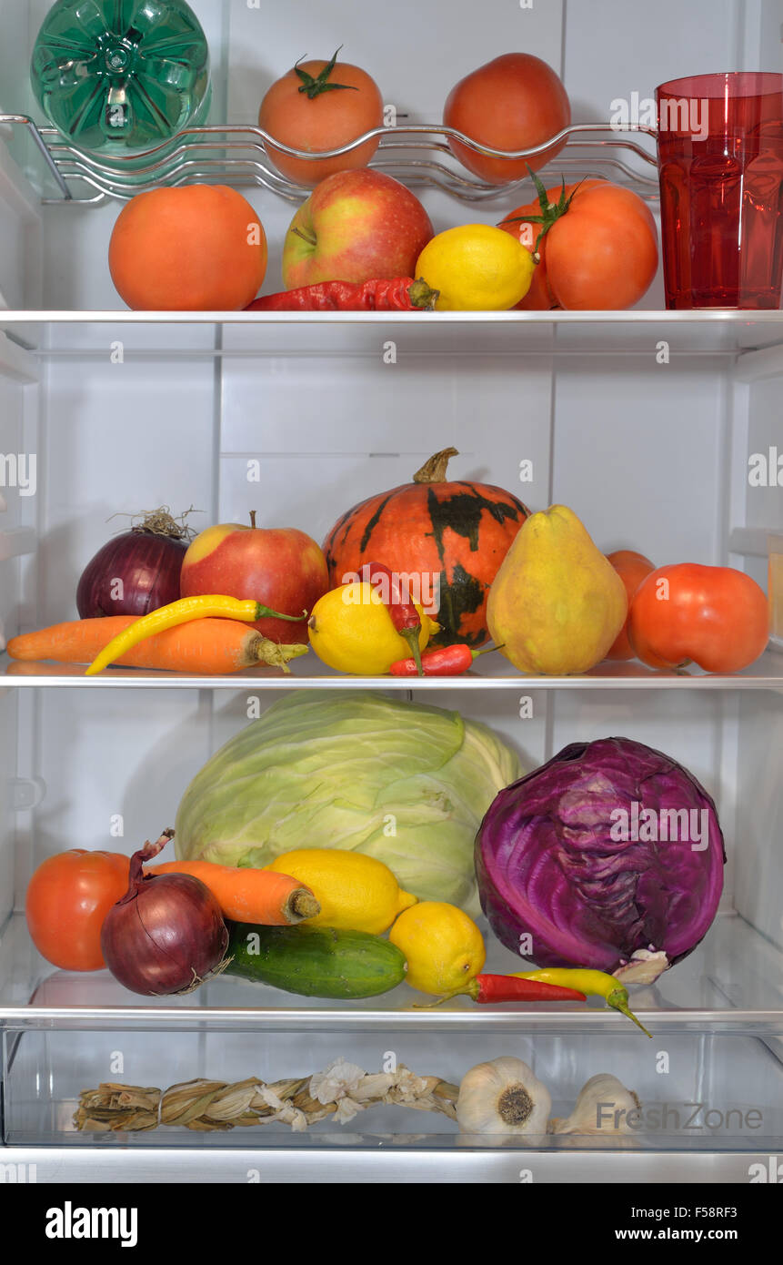 Refrigerator shelves with fresh fruits, vegetables and water Stock Photo