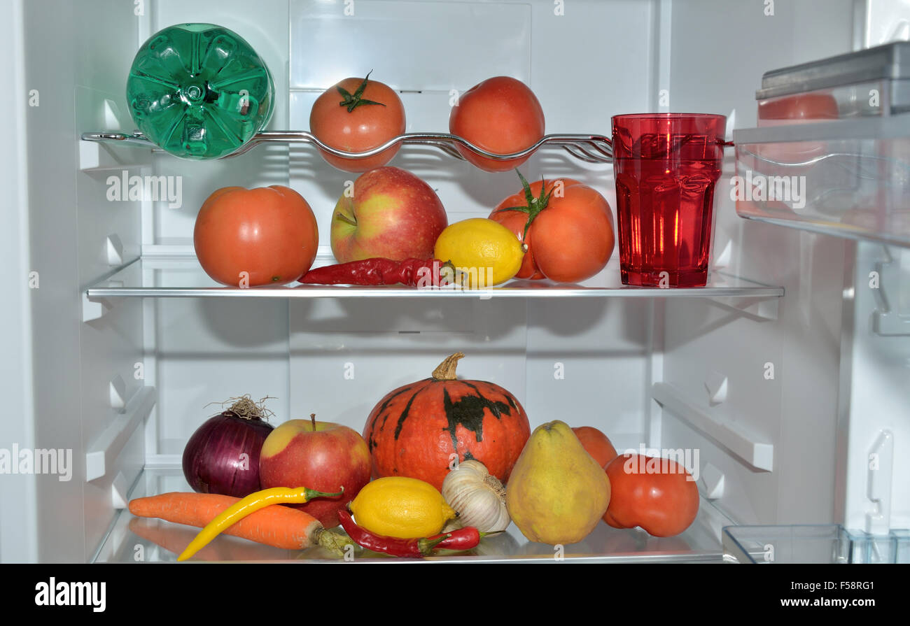 Colorful fruits, vegetables and water on refrigerator shelves Stock