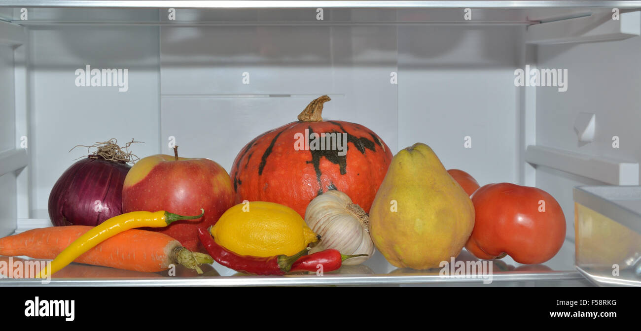Colorful fruits and vegetables on refrigerator shelf Stock Photo