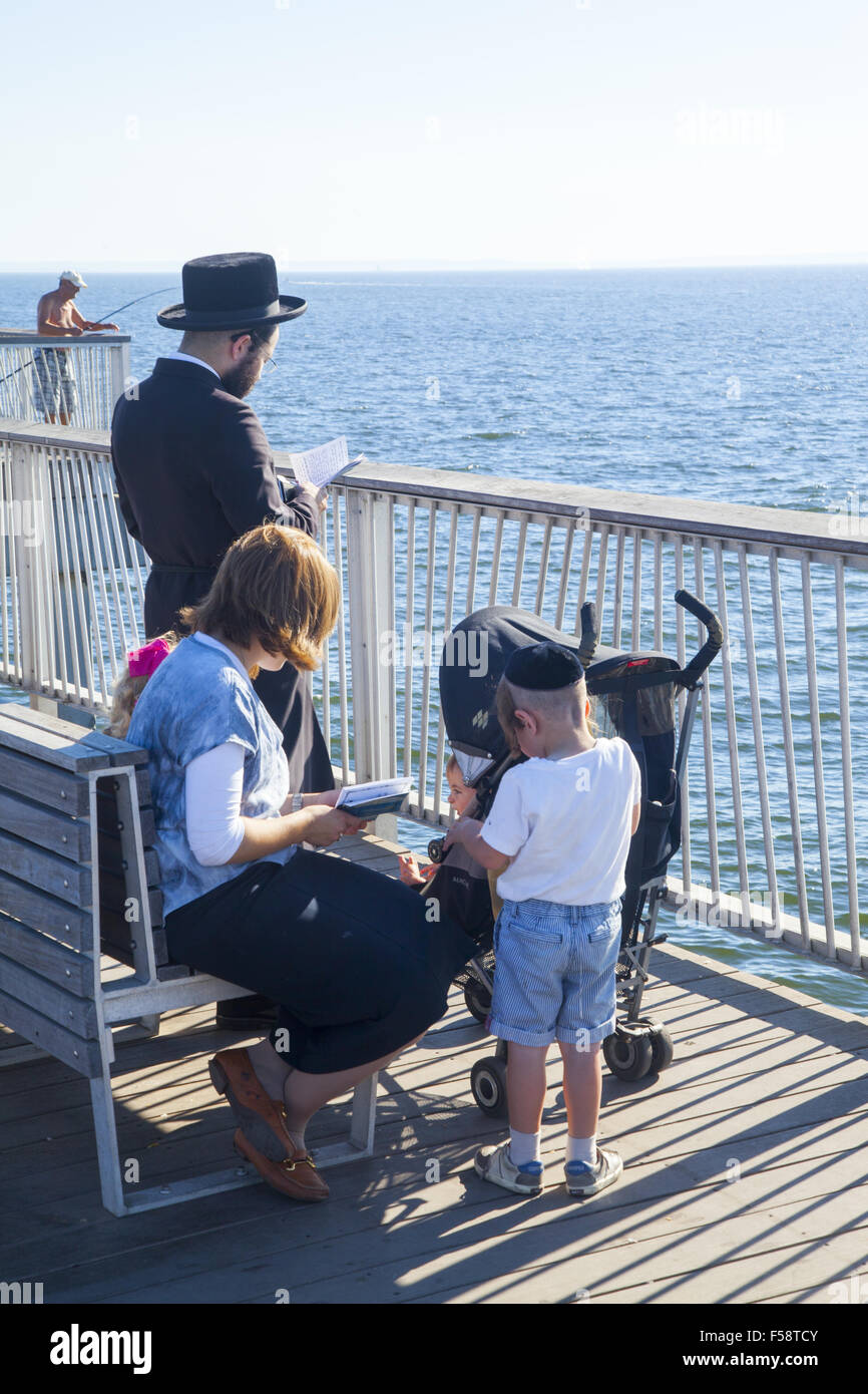 Orthodox Hasidic Jewish family saying prayers during the High Holy Days on the pier at Coney Island, Brooklyn, New York. Stock Photo