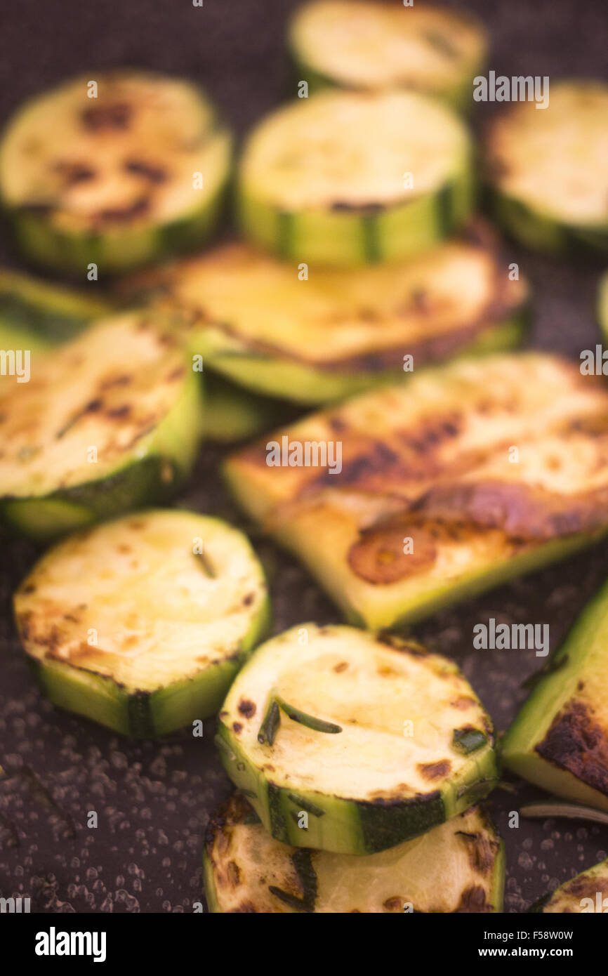 Frying zucchini fried courgettes vegetables and chopped rosemary herbs