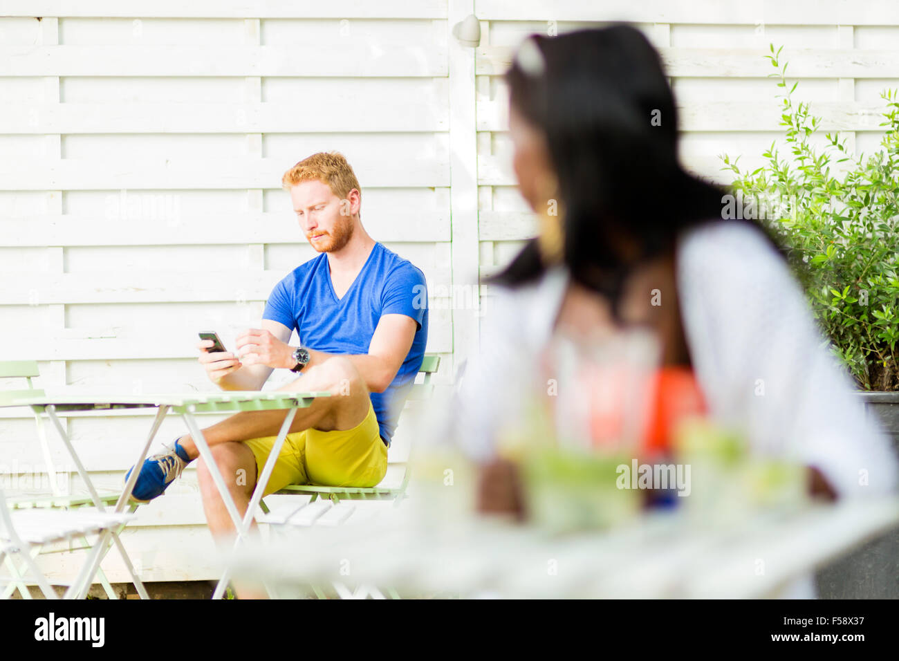 Beautiful black woman looking towards a handsome man in a cafe outdoors Stock Photo