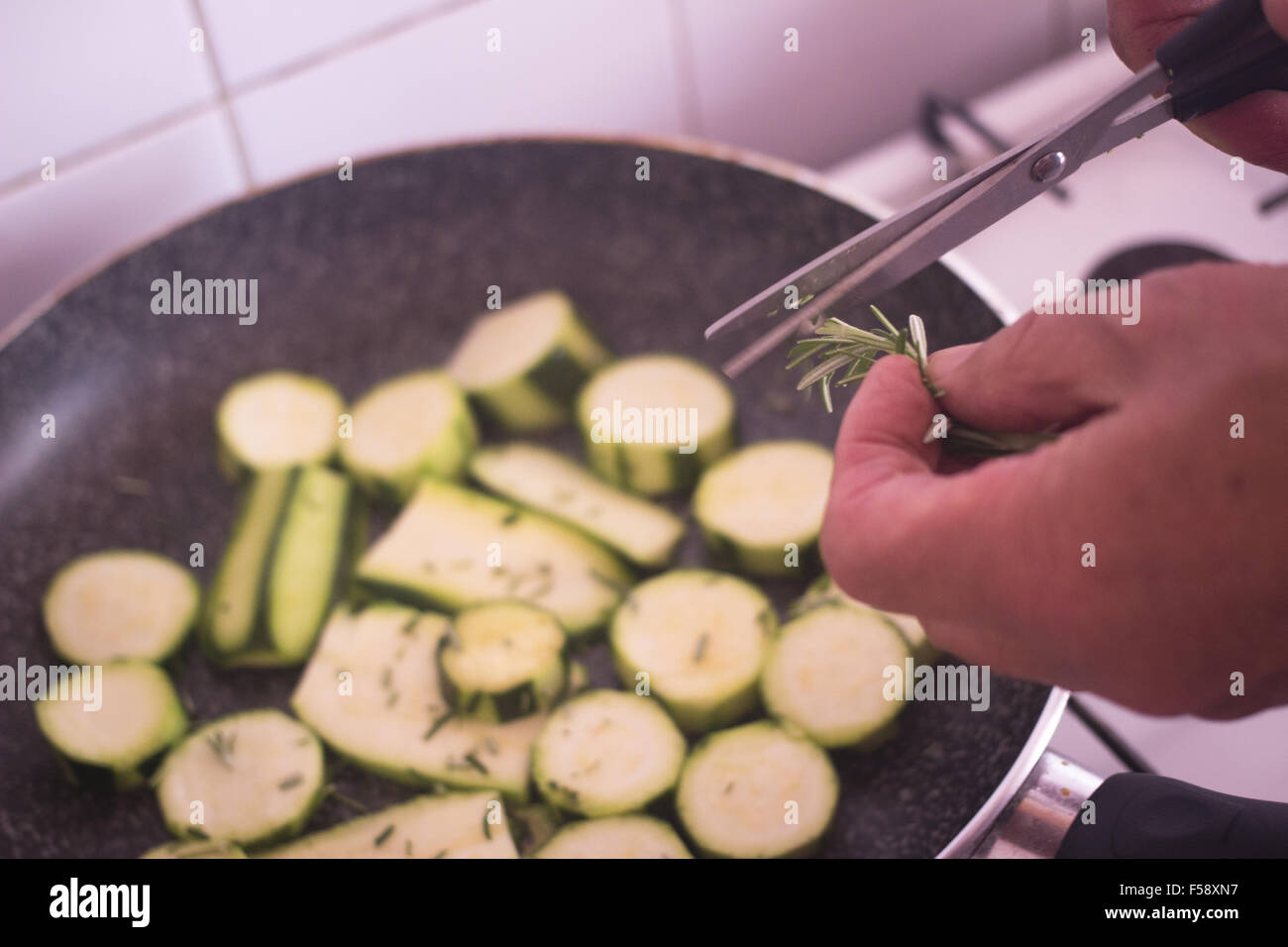 Frying zucchini fried courgettes vegetables and chopped rosemary herbs