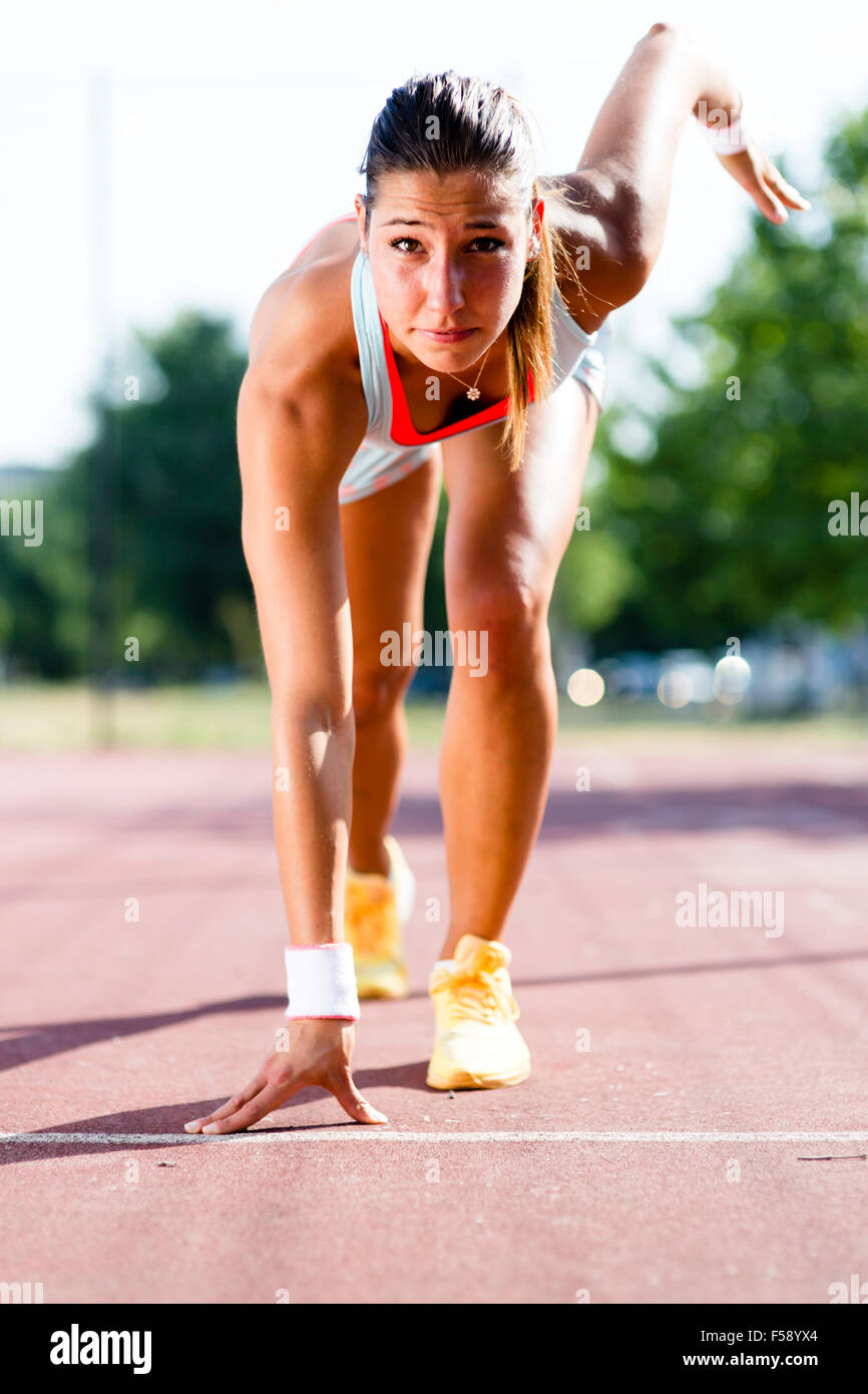 Beautiful female sprinter getting ready for the run during summer Stock Photo