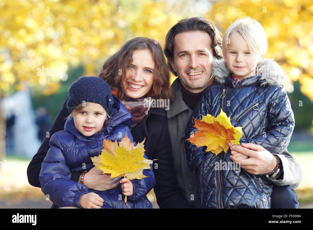 Portrait of a happy family in autumn park with maple leaves Stock Photo ...