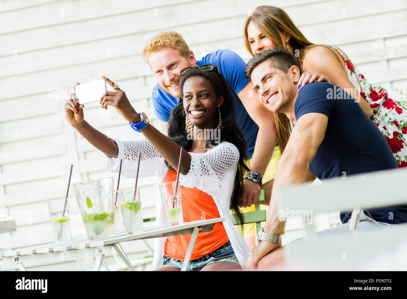A group of friends sitting a table and talking smiling while taking ...