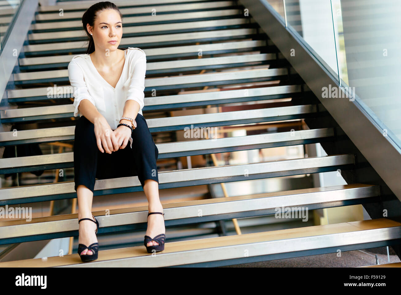 Businesswoman sitting on stairs and thinking. Fashion style photo Stock Photo