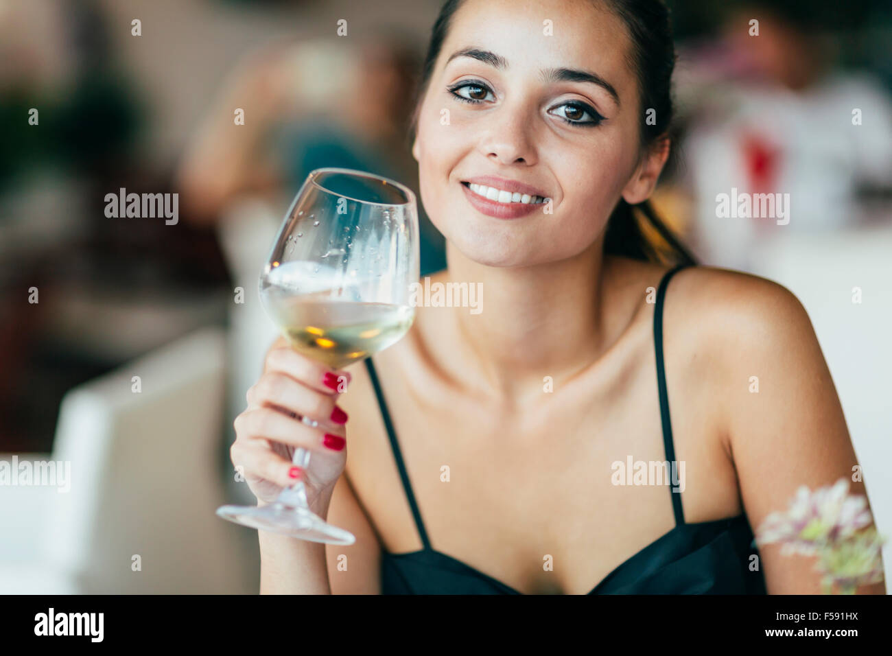 Beautiful woman tasting wine while sitting in restaurant Stock Photo