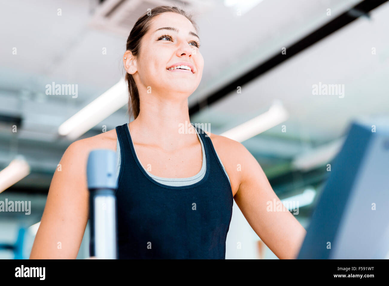 Beautiful young lady using the elliptical trainer in a gym in a ...