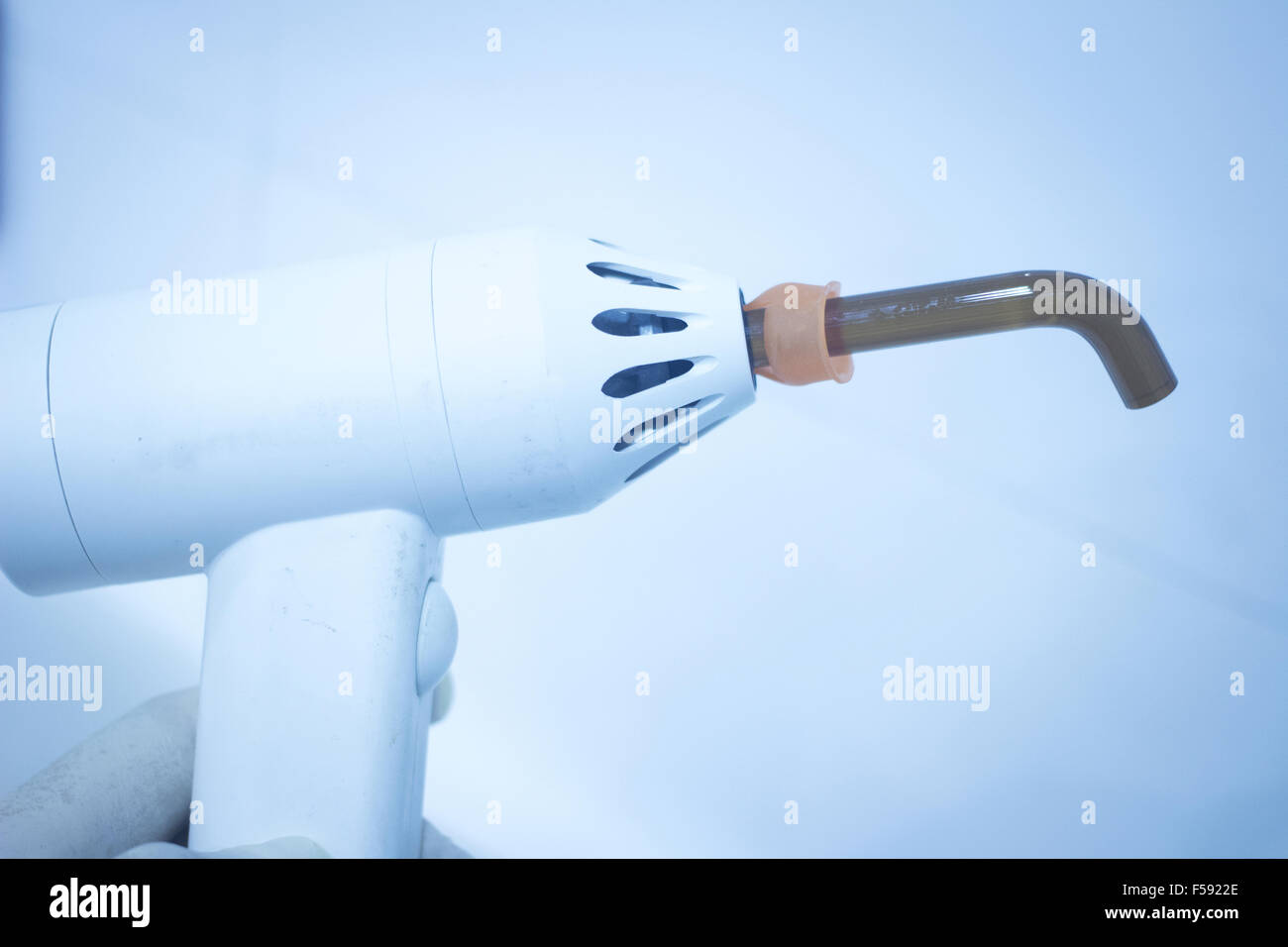 Dental filling gun in dentist hand in clinic office photo Stock Photo