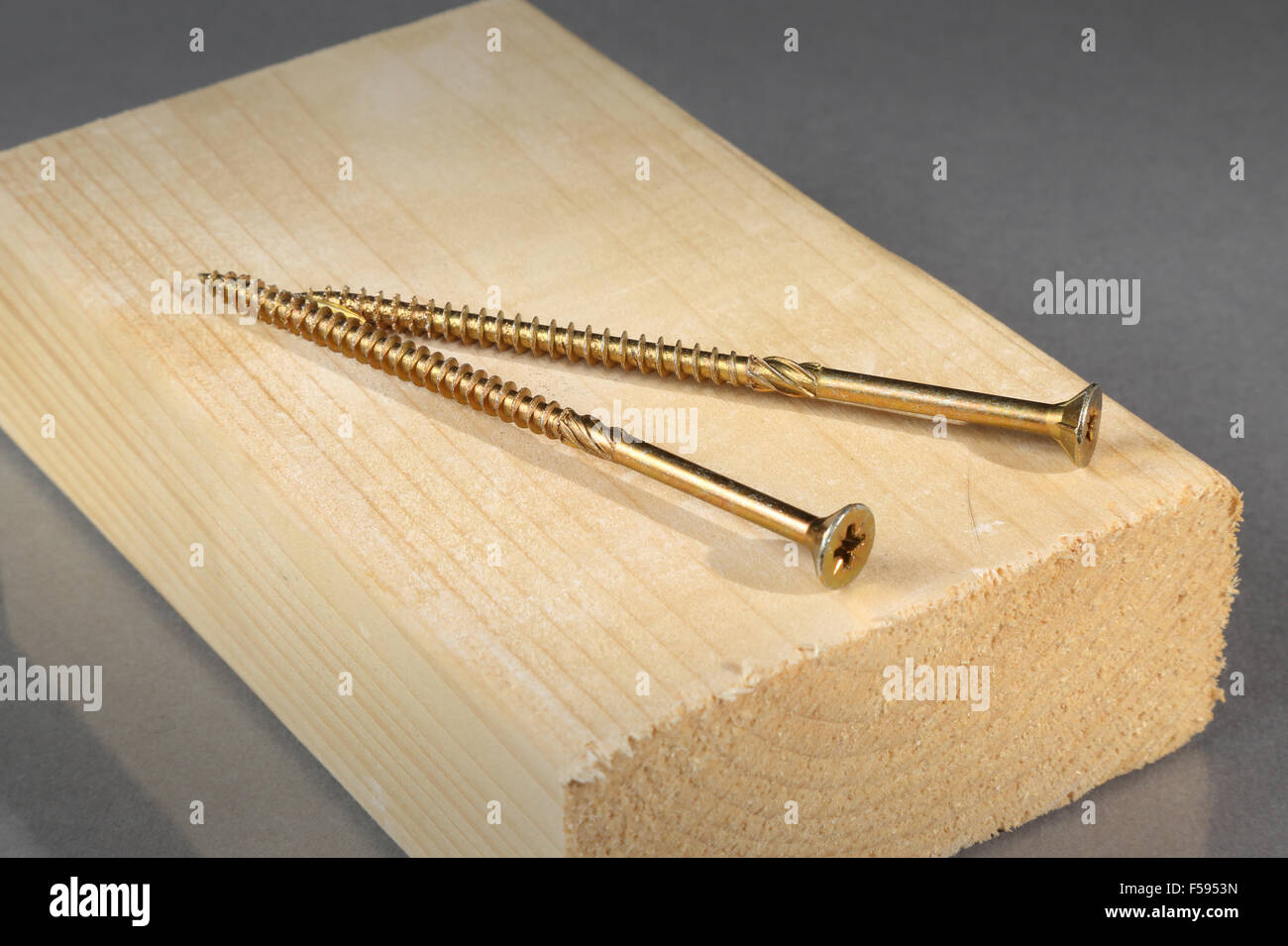 two brass wood screws shown on a block of timber Stock Photo - Alamy