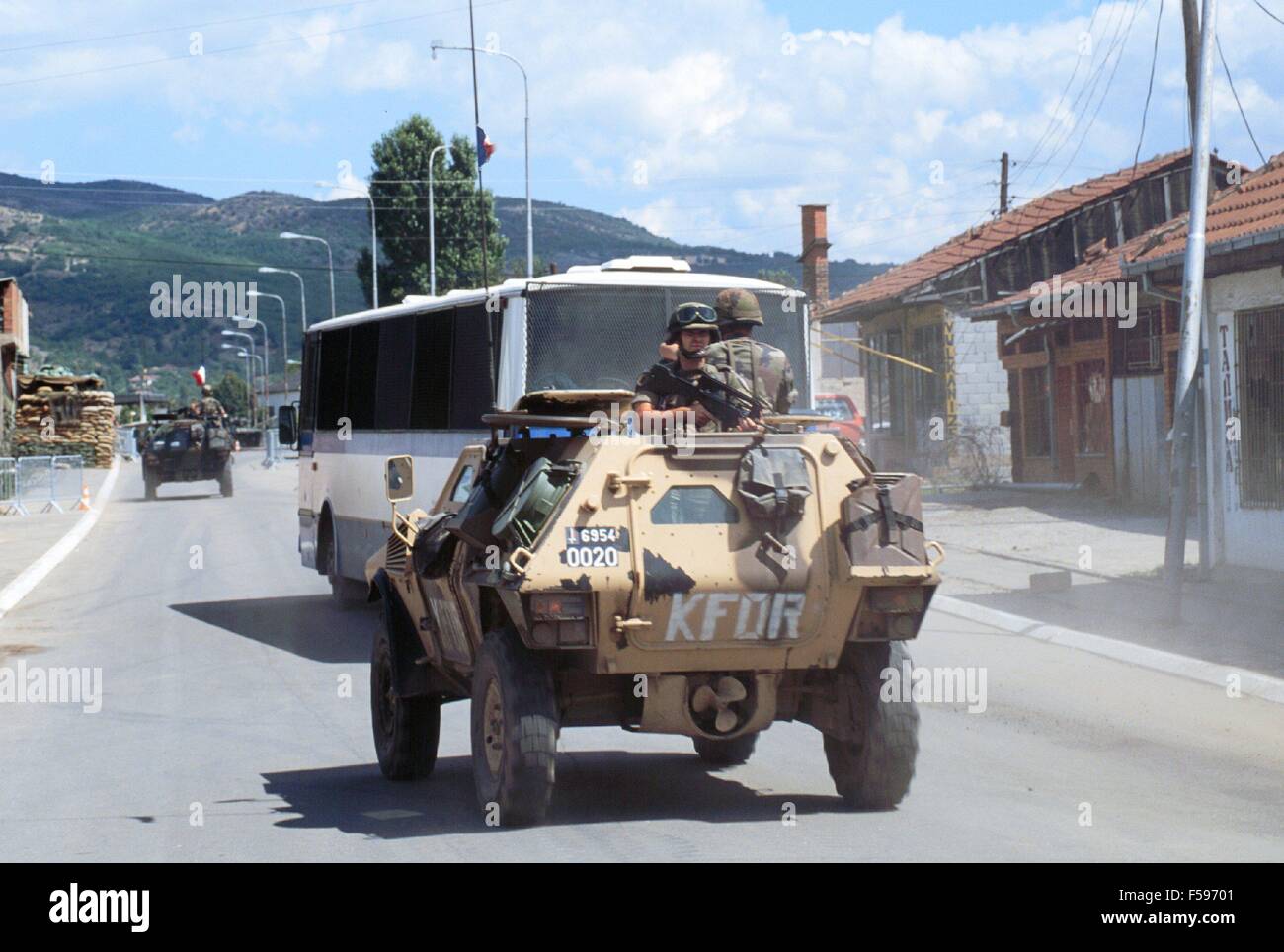 NATO intervention in Kosovo, July 2000, French armored car escorts Serbian bus in the Albanian zone of Mitroviza town Stock Photo