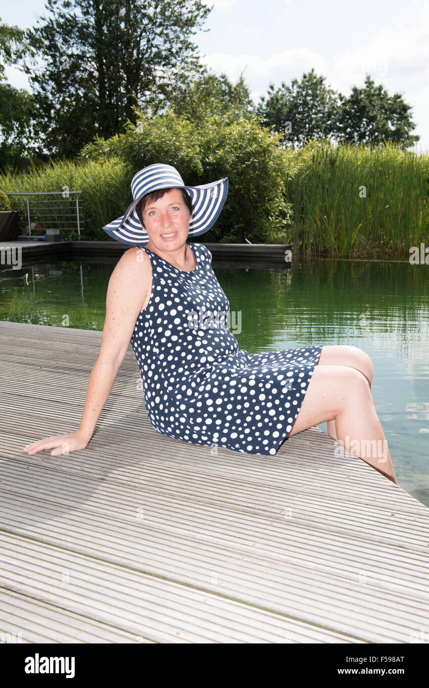 attractive woman siiting with legs in  the pool Stock Photo