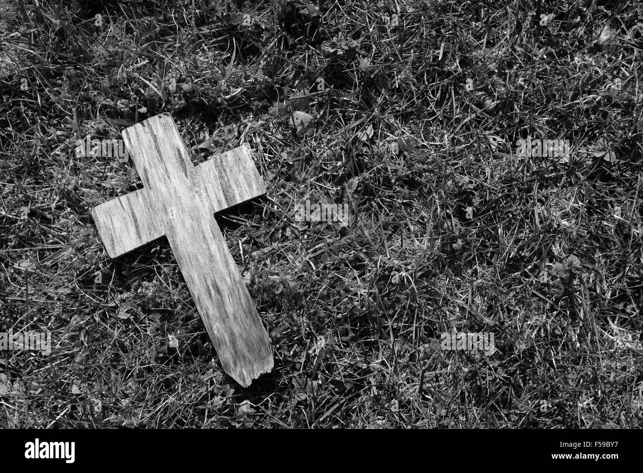 Small weathered cross on a background of grass and moss with copy space - monochrome processing Stock Photo
