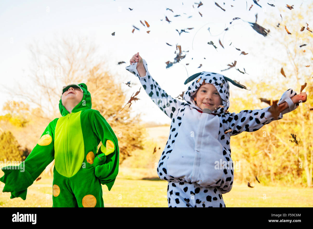 Two boys in costume catching and throwing leaves Stock Photo